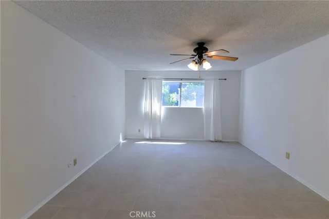 an empty room with windows and chandelier fan