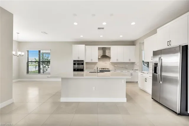 a large kitchen with stainless steel appliances kitchen island a large counter top and a refrigerator