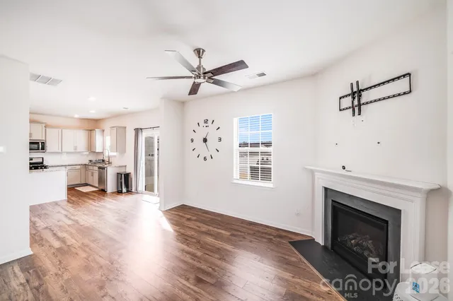 a view of a livingroom with a fireplace a ceiling fan and wooden floor
