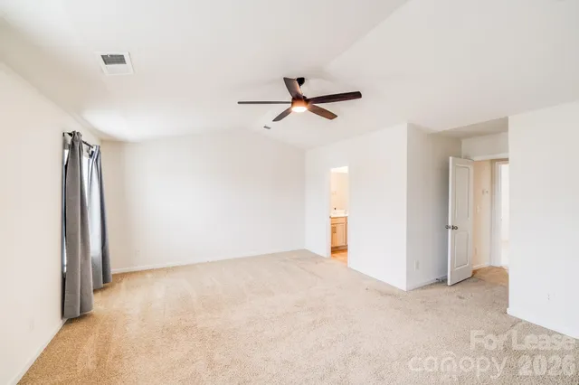 a view of a room with a ceiling fan and carpet