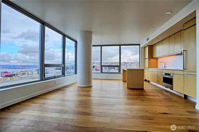 a view of an empty room with window and wooden floor