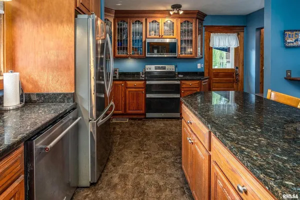 a kitchen with kitchen island granite countertop a stove top oven a sink and dishwasher
