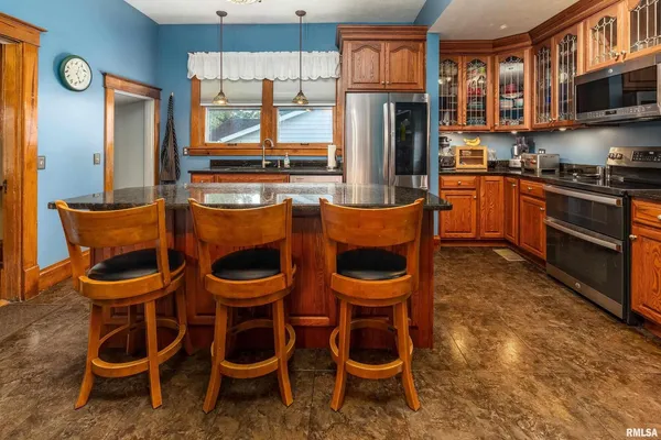 a kitchen with granite countertop lots of wooden furniture and stainless steel appliances