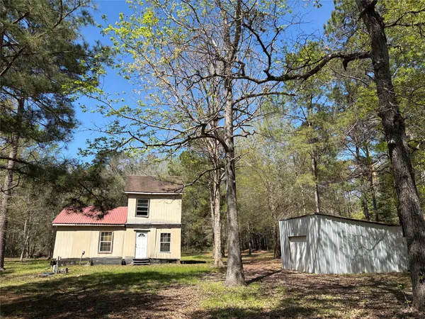 a view of a yard in front of a house with large tree