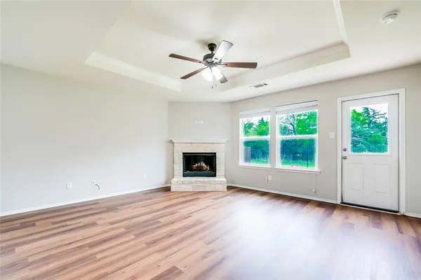 an empty room with windows fireplace and a ceiling fan