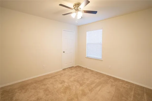 an empty room with a window and a ceiling fan