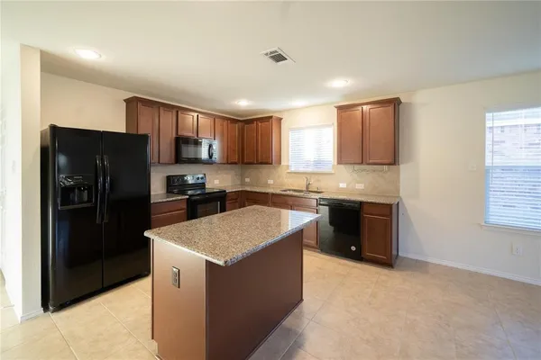 a kitchen with a refrigerator a sink a stove a microwave a counter top and cabinets