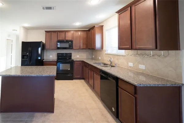 a large kitchen with granite countertop a sink and cabinets