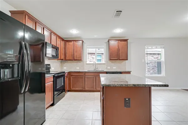 a kitchen with stainless steel appliances granite countertop wooden cabinets a stove top oven and granite counter tops