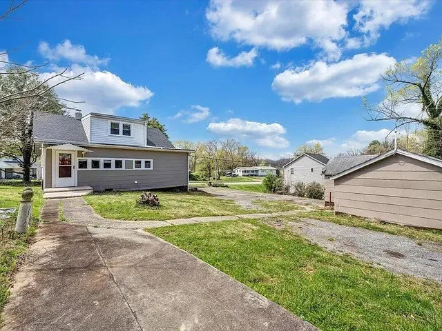 a view of a house with a yard and table and chairs under an umbrella