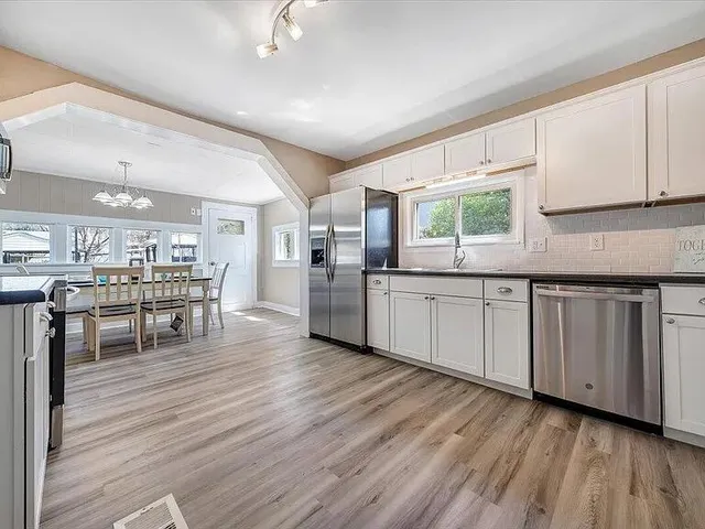 a kitchen with white cabinets and wooden floor