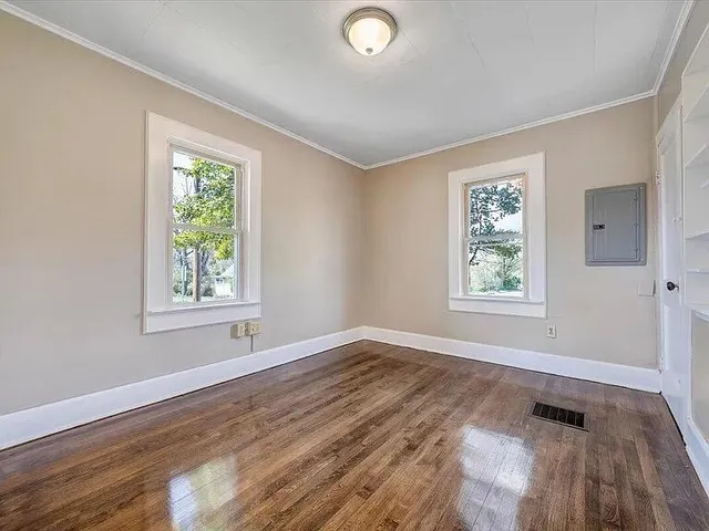 a view of empty room with wooden floor and fan