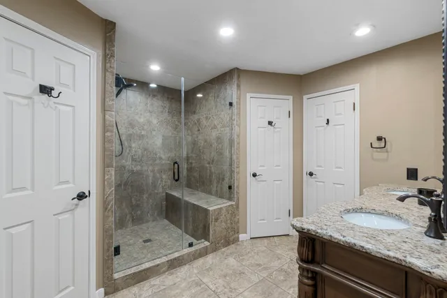 a bathroom with a granite countertop sink a shower and mirror