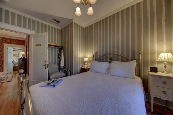 a bedroom with a bed a chandelier and a flat tv screen on dresser