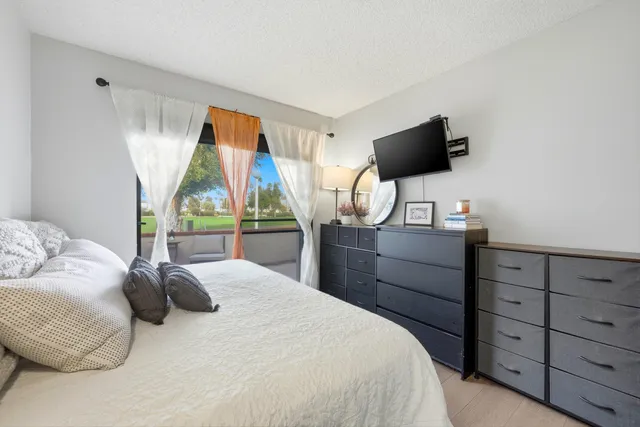 a bedroom with a bed television on desk and a window