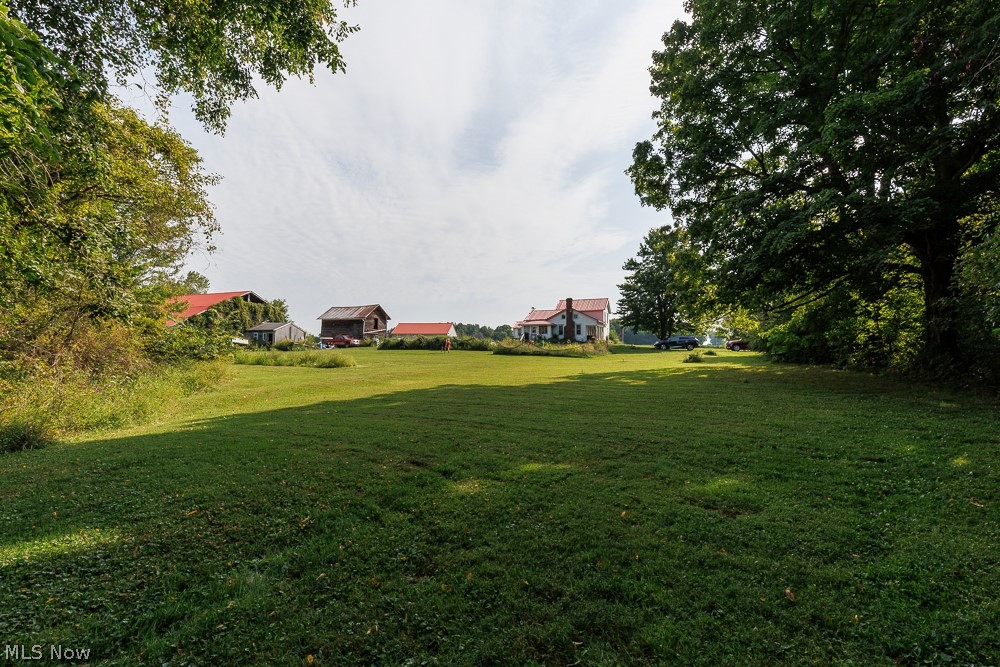 5366 Zenobia Road Wakeman, OH 44889 - Photo 19 of 25 Expansive green lawn with mature trees and a distant white residential structure featuring a red roof and chimney