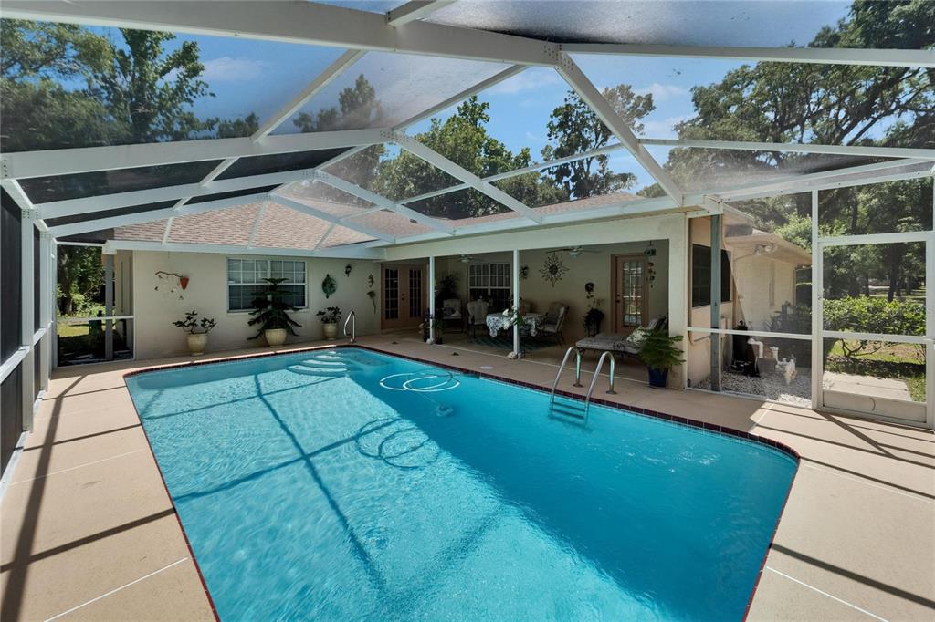 11120 Lu Wista Road Brooksville, FL 34601 - Photo 31 of 50 a view of a patio with table and chairs potted plants and large tree