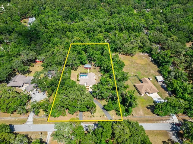an aerial view of residential house with outdoor space and trees all around