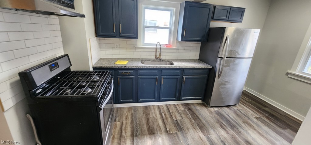 1514 Clermont Road Cleveland, OH 44110 - Photo 4 of 16 Kitchen with stainless steel appliances, dark wood-style floors, light stone counters, blue cabinets, and tasteful backsplash