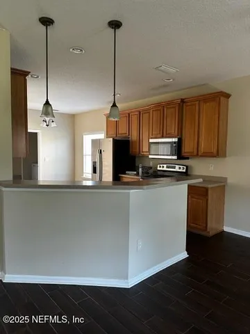 a kitchen with stainless steel appliances granite countertop a refrigerator a sink dishwasher a stove and a microwave oven on granite countertops