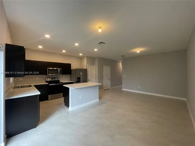 a view of kitchen with stainless steel appliances kitchen island fireplace a sink and a large window