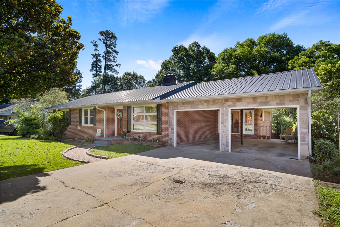512 East Fredericks Street Anderson, SC 29621 - Photo 2 of 31 Brick and stone accents define this charming residence, offering a welcoming carport entry.