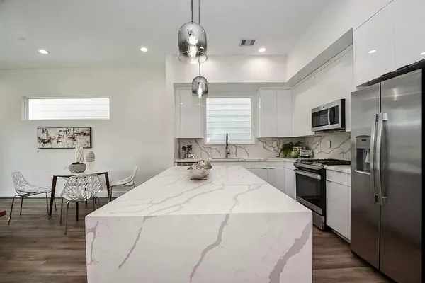 a large kitchen with sink a refrigerator and chairs