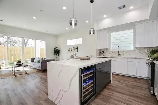 a kitchen with a stove a sink a kitchen island with wooden floor and white cabinets