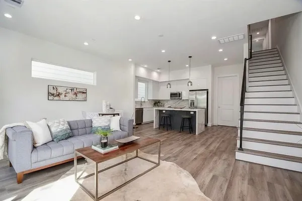 a living room with stainless steel appliances furniture and wooden floor