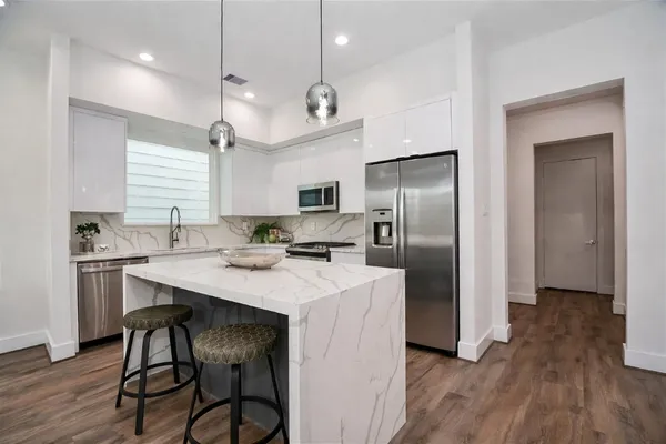 a kitchen with stainless steel appliances granite countertop a refrigerator a sink dishwasher a stove and a refrigerator with wooden floor