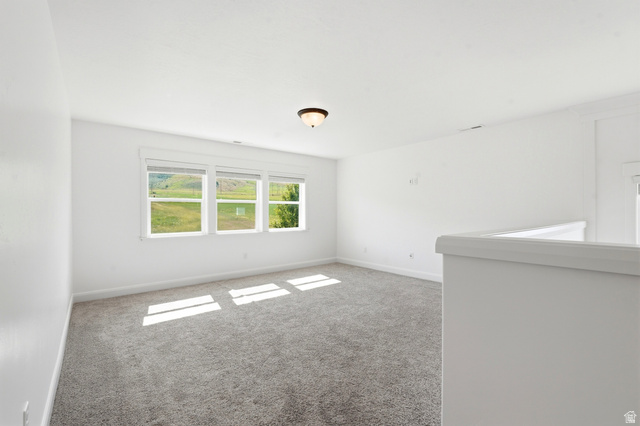 338 Windy Rdg Drive Smithfield, UT 84335 - Photo 22 of 63 Spacious room featuring three large windows, gray carpet, white walls, white trim, and a ceiling-mounted light fixture