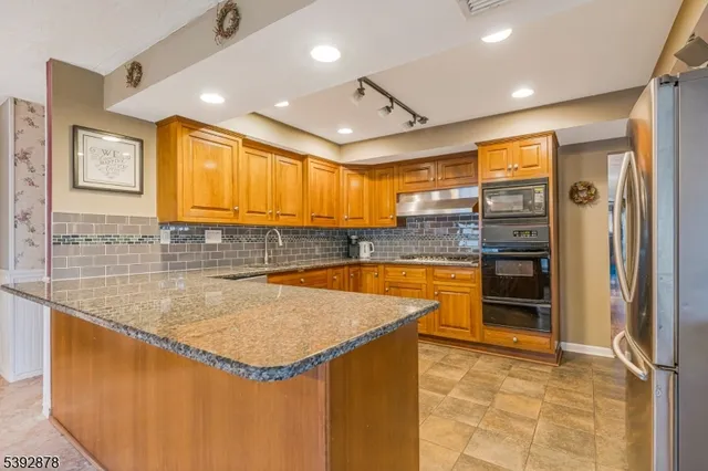 a kitchen with stainless steel appliances granite countertop a sink a stove and a refrigerator