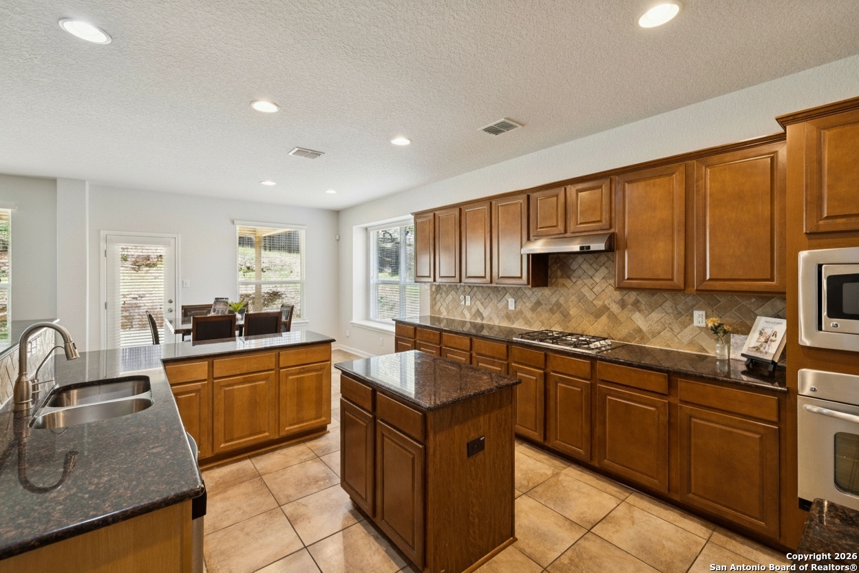 23567 7 Winds San Antonio, TX 78258 - Photo 18 of 49 a kitchen with granite countertop a sink stove and cabinets