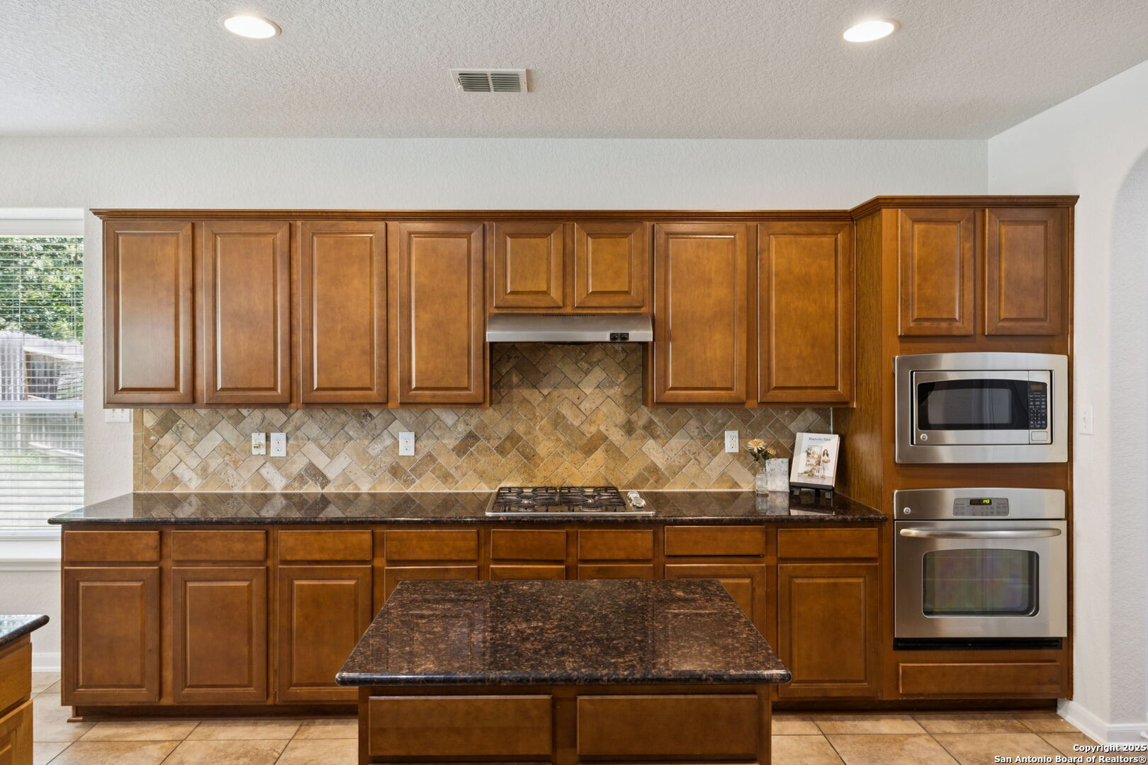 23567 7 Winds San Antonio, TX 78258 - Photo 20 of 49 a kitchen with granite countertop a stove a sink and a microwave