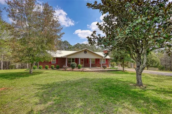 a view of a big house with a big yard and large trees