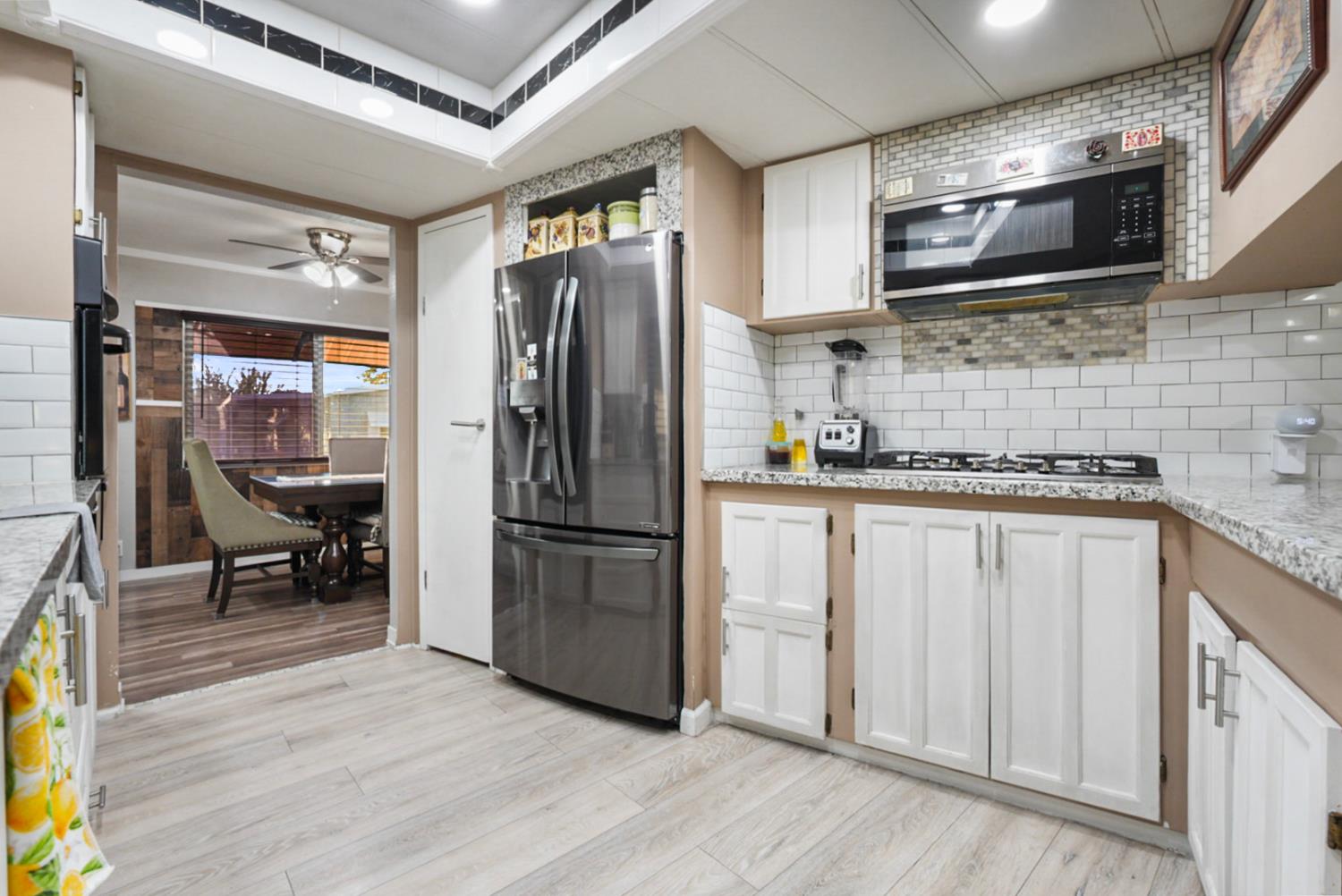 4837 Faith Home Road, Unit 162 Ceres, CA 95307 - Photo 11 of 45 a kitchen with stainless steel appliances granite countertop a refrigerator a microwave oven a sink dishwasher and white cabinets with wooden floor