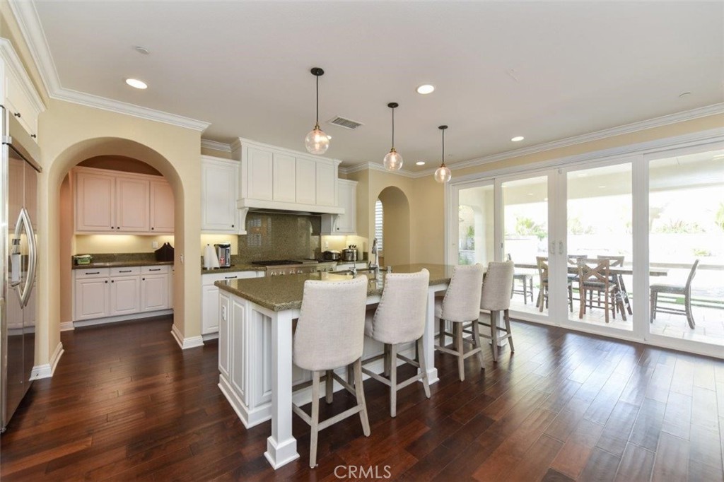 107 Fairgrove Irvine, CA 92618 - Photo 8 of 31 a kitchen with stainless steel appliances kitchen island granite countertop a stove a refrigerator a sink a dining table and chairs with wooden floor