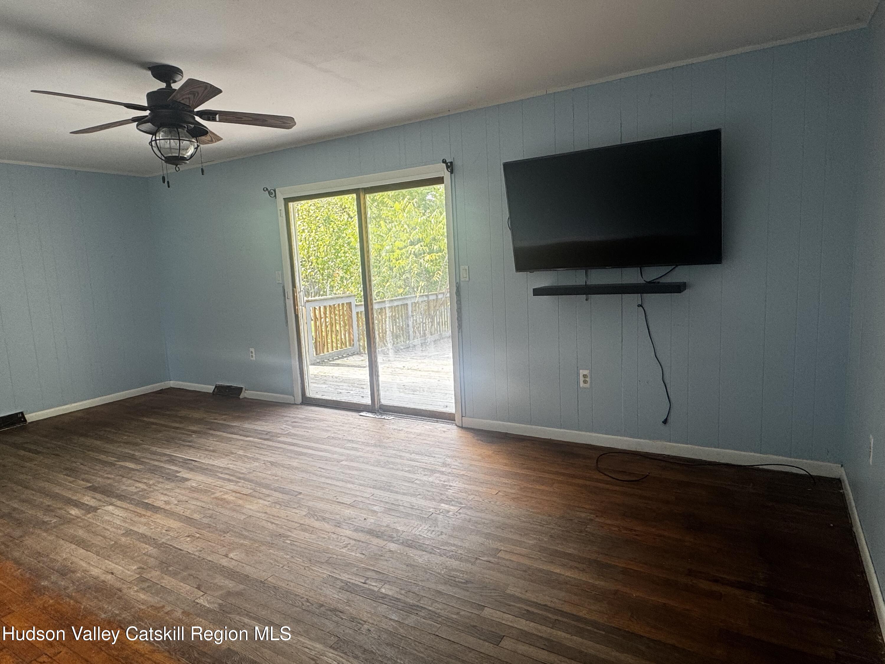 14 Snyder Circle Stone Ridge, NY 12484 - Photo 3 of 19 a view of a livingroom with a flat screen tv wooden floor and a ceiling fan