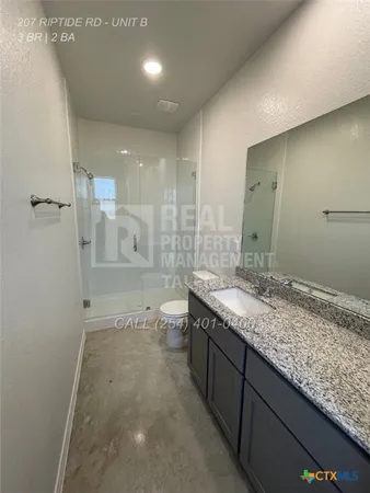 a bathroom with a granite countertop sink a toilet and shower