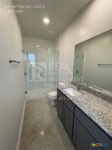 a bathroom with a granite countertop sink a toilet and shower