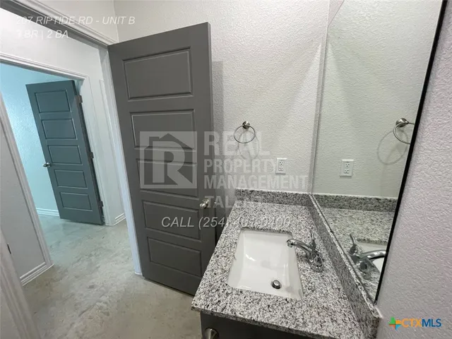 a bathroom with a granite countertop sink a toilet and shower