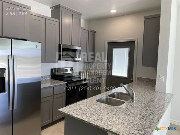 a kitchen with kitchen island granite countertop a sink stove and refrigerator