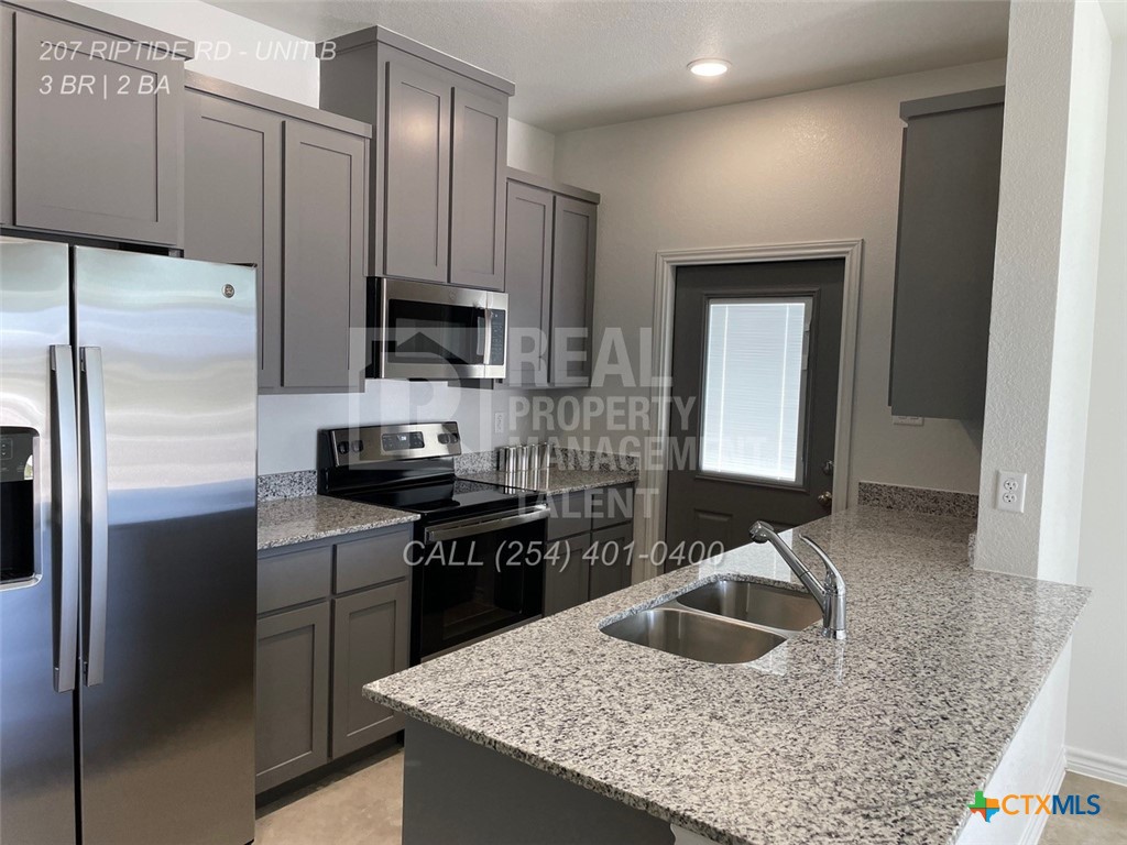 207 Riptide Road Temple, TX 76501 - Photo 8 of 13 a kitchen with kitchen island granite countertop a sink stove and refrigerator