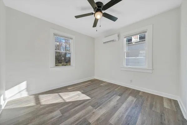 a view of empty room with wooden floor and fan