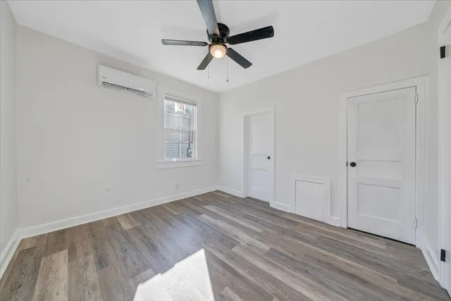 an empty room with wooden floor ceiling fan and windows