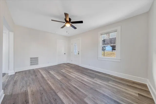 a view of empty room with wooden floor and fan