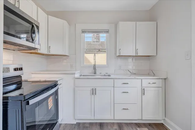 a kitchen with granite countertop white cabinets stainless steel appliances and a sink