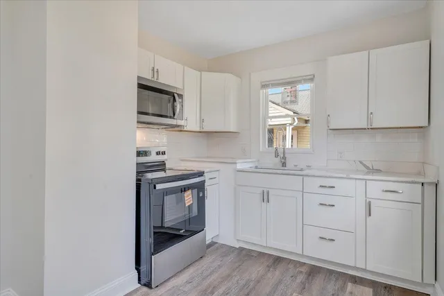 a kitchen with white cabinets stainless steel appliances and sink