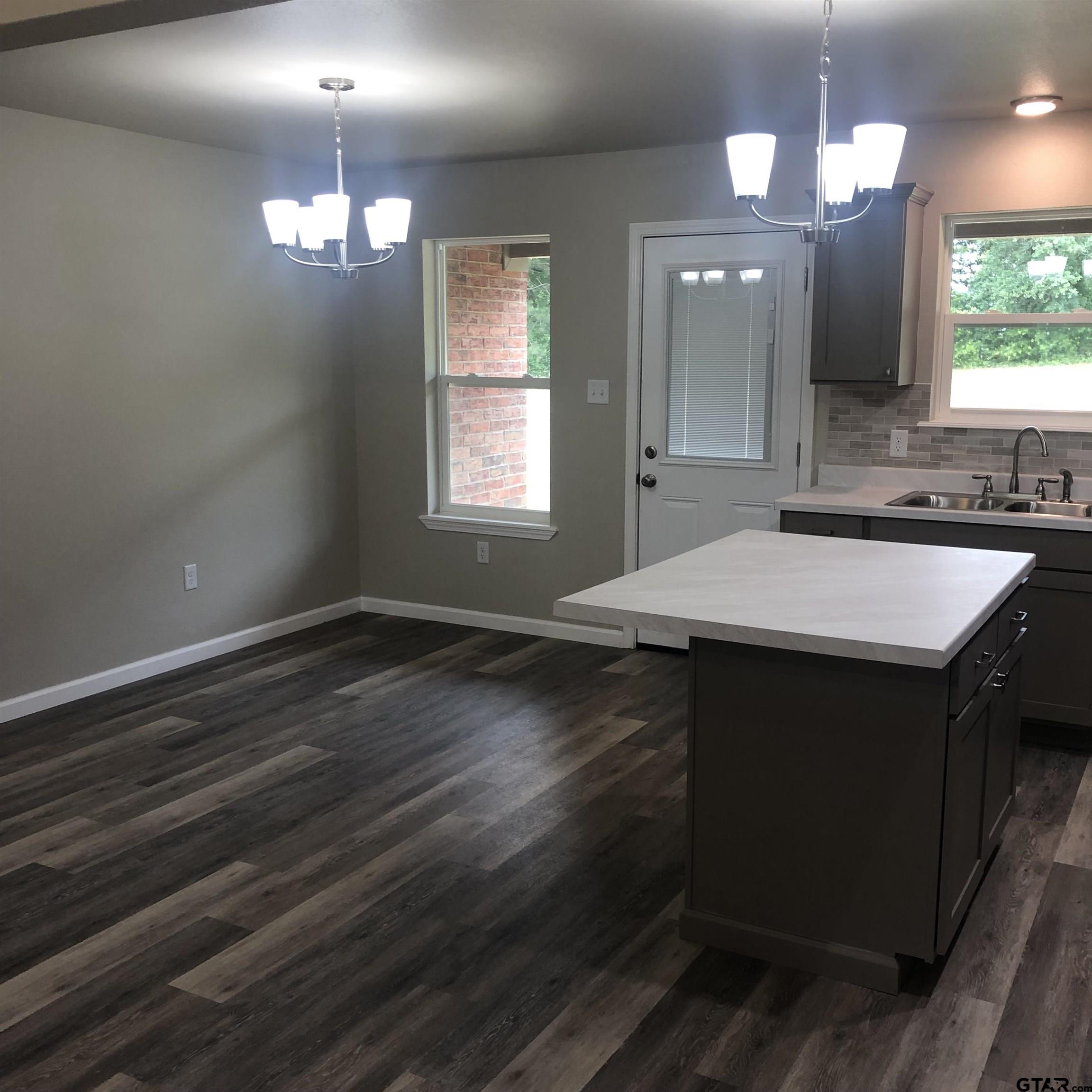 105 Meadows Lane Maud, TX 75567 - Photo 18 of 19 a kitchen with a sink chandelier and wooden floor