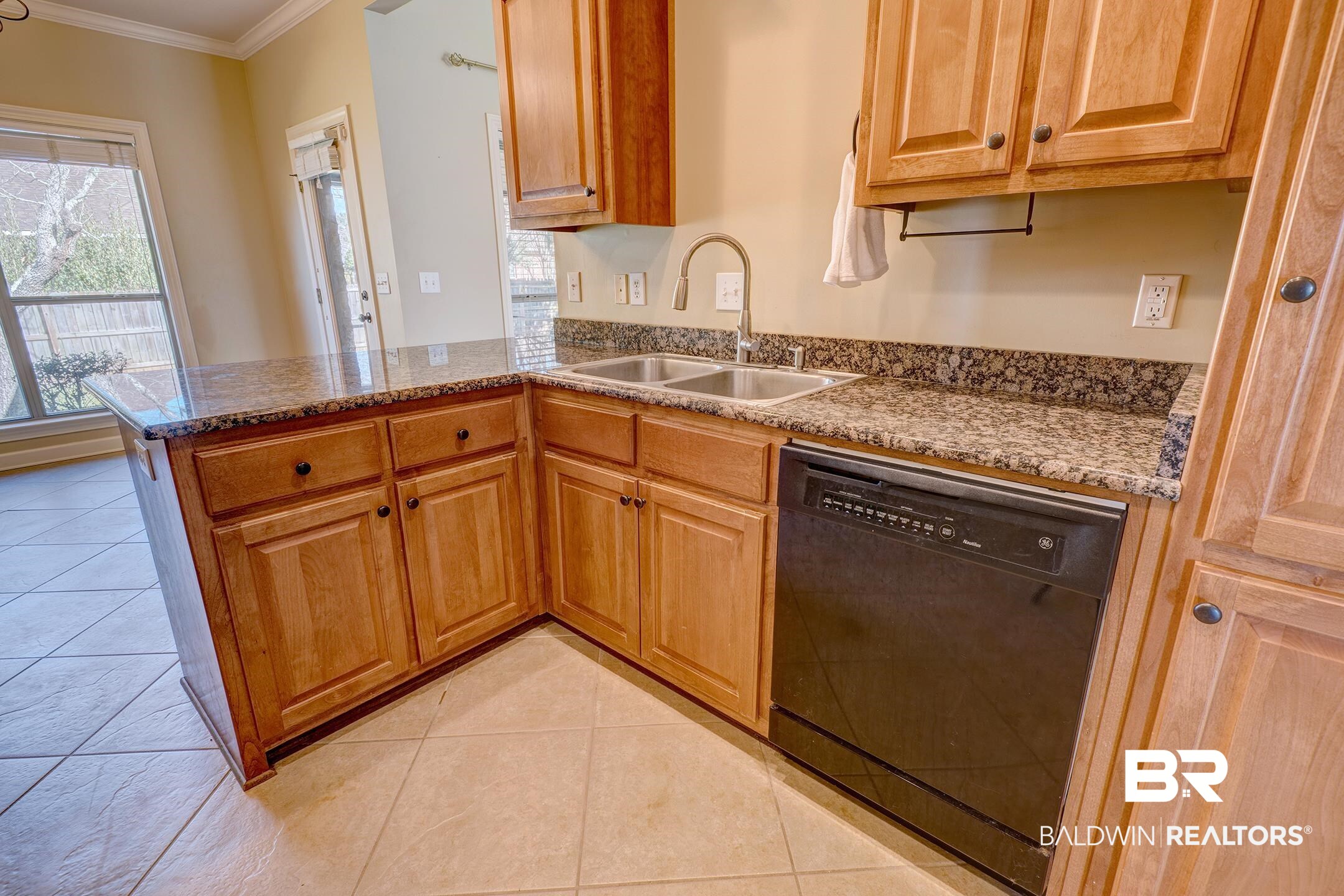 9421 Collier Loop Daphne, AL 36526 - Photo 13 of 31 Kitchen featuring black dishwasher, crown molding, light tile patterned flooring, light stone counters, and a peninsula